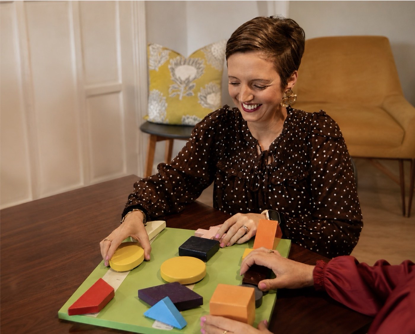 A therapist guiding a client through a shape-sorting exercise at a desk